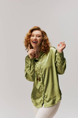 Kıvırcık saçlı neşeli genç bir kadın neşeli poz vermekten, mutluluk ve yaratıcılık saçmaktan hoşlanır..