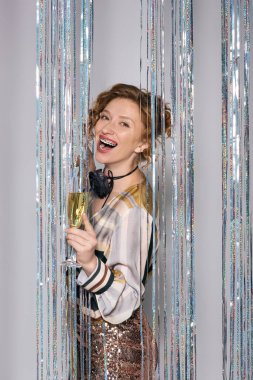 Celebrating the festive spirit, a young woman posing cheerfully while enjoying a glass of champagne. clipart