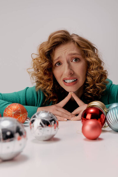 A young woman with curly hair and colorful ornaments surround her.