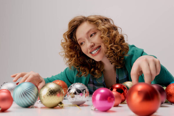 Веселая молодая женщина любит позировать, играя с блестящими орнаментами вокруг нее.