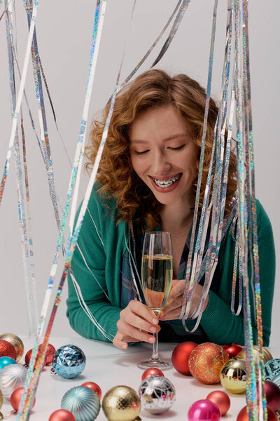 Joyful moment as a young woman posing cheerfully surrounded by glittering decorations and festive cheer.
