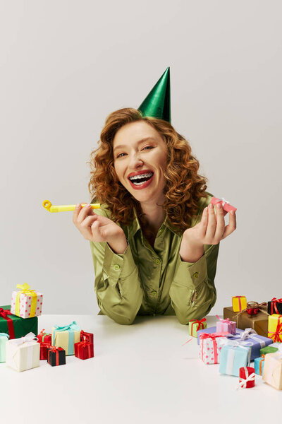 Молодая женщина с вьющимися волосами улыбается, позируя в оживленной обстановке.