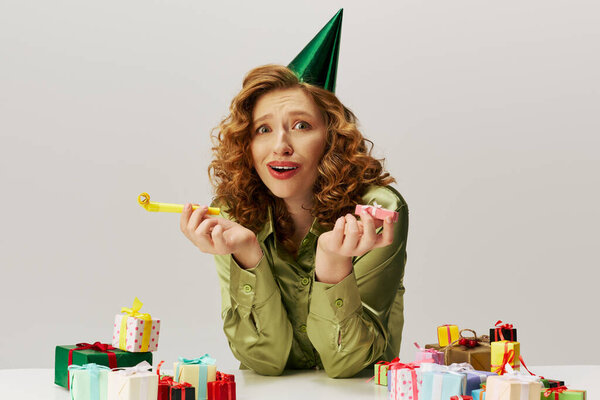 Молодая женщина с кудрявыми волосами с энтузиазмом позирует в праздничной атмосфере.