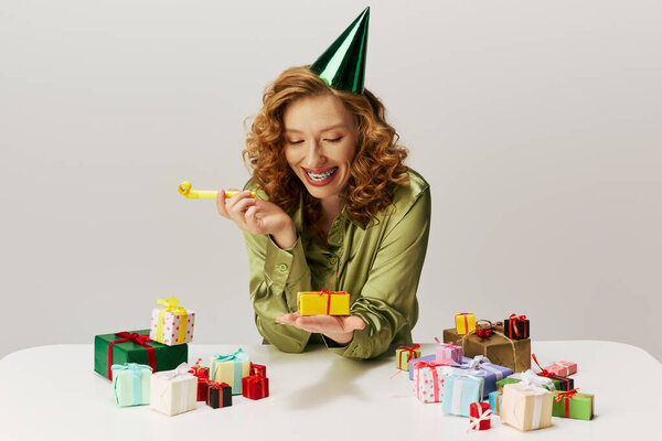 A cheerful young woman enthusiastically posing while wearing a party hat.