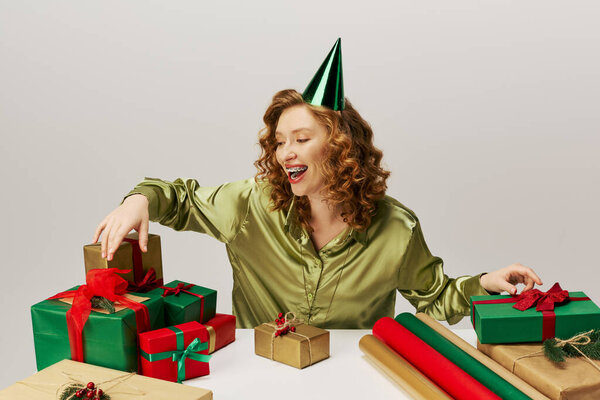 The young woman is happily posing cheerfully with vibrant wrapping paper and ribbons at a lively event.