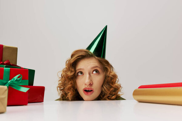 A young woman with a surprised expression posing while wearing a party hat.