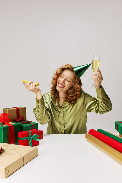 A young woman is enjoying a festive moment while posing cheerfully and celebrating with a drink.