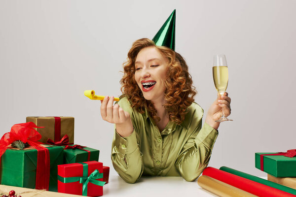 Молодая женщина с вьющимися волосами празднует, позируя и наслаждаясь напитком.