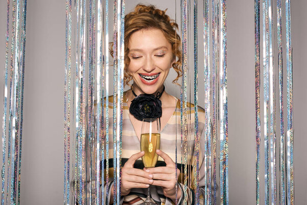 A young woman smiles brightly as she posing cheerfully, radiating joy amidst festive decorations.