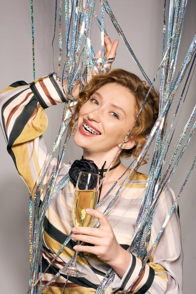 Веселая молодая женщина в окружении красочных лент и украшений.