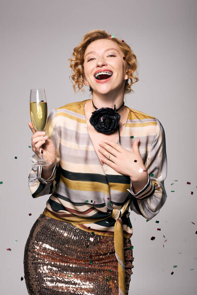 Веселая женщина празднует со смехом, держа напиток в окружении праздничных украшений.