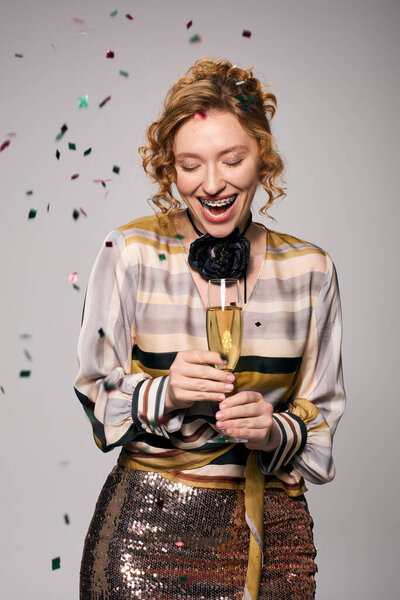 Молодая женщина радостно позирует, улыбаясь на празднике вокруг нее.