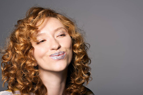 Веселая молодая женщина весело позирует, демонстрируя свой артистический талант и сверкающие губы..