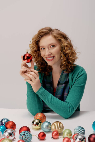 A cheerful young woman posing cheerfully amidst vibrant holiday decorations.