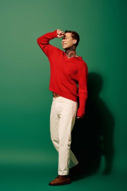 Genç adam eğlenceli bir poz veriyor, canlı bir atmosferin keyfini çıkarırken dövmelerini gösteriyor..