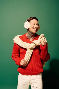 Dövmelerle süslenmiş bu genç adam renkli bir kazak giyerken neşe saçıyor..