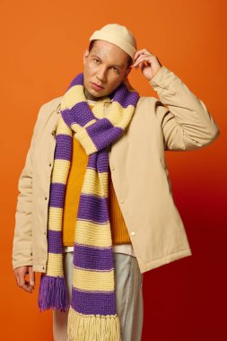 Şık bir genç adam canlı bir eşarp, dövmeler ve şapkasını düzeltir..