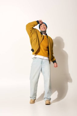 Dövmeleri olan genç bir adam dans ederek mutluluğu ifade eder, canlı stilini ve enerjisini gösterir..