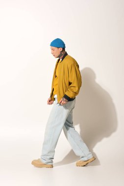 Dövmelerle süslenmiş genç bir adam kendine güvenerek dolaşır, kişisel stili ve yaratıcılığını yansıtır..