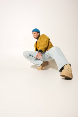 Genç bir adam dövmelerini sergilerken rahat sokak kıyafetleri içinde pozlar veriyor..