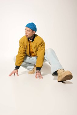 Anlamlı dövmeleri olan genç bir adam benzersiz tarzını sergiliyor ve modern bir ortamda poz veriyor..