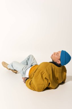 Moda kıyafetleri içinde genç bir adam yerde uzanırken sakin bir anın tadını çıkarıyor..