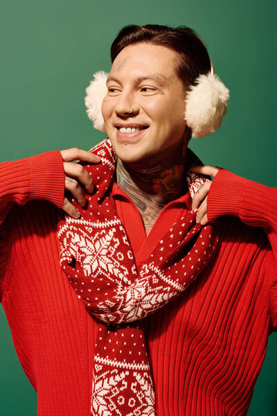 A young man wearing a warm red sweater and scarf smiles brightly while embracing the festive season.