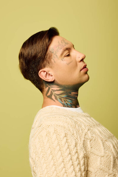 A young man showcases intricate tattoos on his neck while gazing thoughtfully to the side.