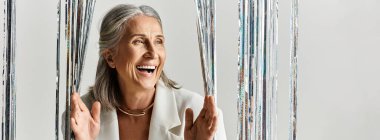 Gri saçlı güzel olgun bir kadın Noel 'i ve yeni yılı neşeyle kutluyor, mutluluk saçıyor..