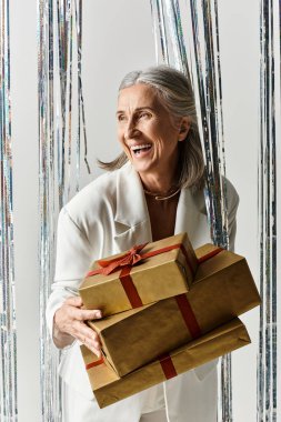 Neşeli, olgun bir kadın, Noel ve yeni yılı zarif bir şekilde kutlayarak, neşeli hediyeler sunar..