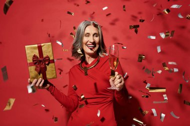 Güzel, olgun bir kadın kadehini kaldırır ve elinde bir hediye tutar. Noel ve yeni yılın şenlikli ruhunu kutlar..