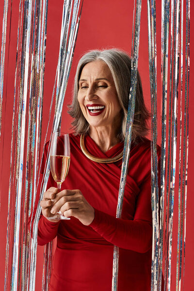 На ярком празднике прекрасная зрелая женщина радостно улыбается во время тоста с бокалом шампанского.