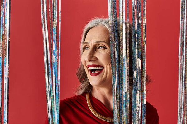Эта красивая зрелая женщина с седыми волосами радостно празднует Рождество и Новый год в праздничной атмосфере.