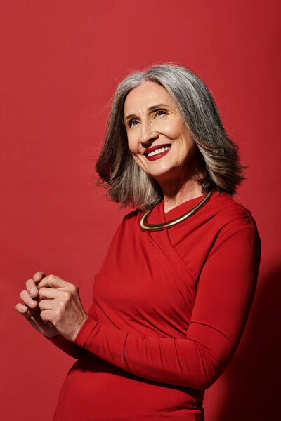 Красивая зрелая женщина с седыми волосами радостно отмечает Рождество и встречает Новый год стильно.