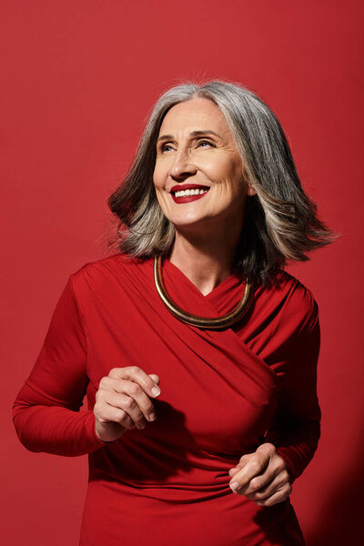 Красивая зрелая женщина с седыми волосами радостно встречает Рождество и Новый год с теплой улыбкой.