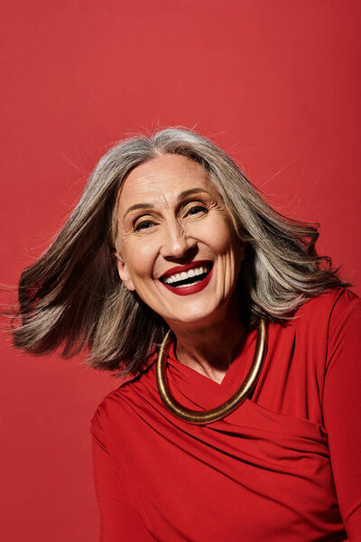 Радостная зрелая женщина с седыми волосами празднует праздничный сезон, олицетворяя тепло и веселье.