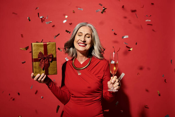 A beautiful mature woman with grey hair joyfully celebrates Christmas and New Year, surrounded by confetti.