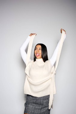 Genç ve güzel bir kadın neşe içinde kazağıyla poz veriyor..