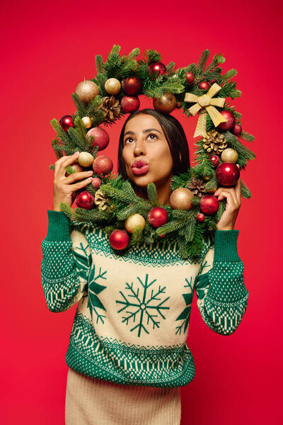 The young woman displays her festive spirit with a colorful wreath full of ornaments.