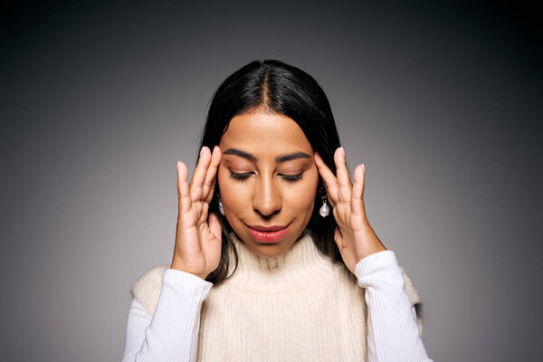 Красивая женщина появляется интроспективно, слегка касаясь своих висков в спокойный момент.