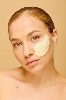 Genç, güzel ve kilolu bir kadın, kendine bakımı sırasında kremsi bir maske takarken rahatlar..