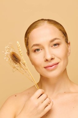 A young plus size woman smiles softly while holding delicate dried flowers. clipart