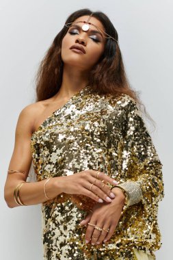 An elegant African American model exudes beauty in shimmering gold attire, captured in a chic studio. clipart