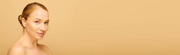 Уверенная в себе молодая женщина подчеркивает свою сияющую кожу и красоту в мягкой, теплой обстановке.