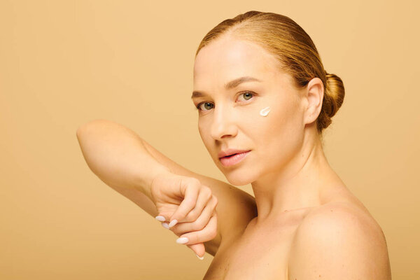 A young plus size woman gently with skincare cream on her cheek, radiating confidence.