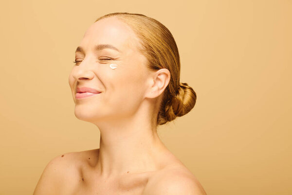 Весёлая женщина плюс размер улыбается со сливками на лице в яркой студии.