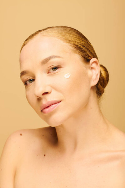 Молодая женщина плюс размер спокойно позирует с кожей на щеке в уютной обстановке.