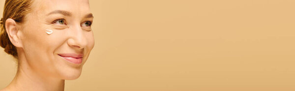 Красивая женщина плюс размер улыбается, нанося кожу на щеку, обнимая уход за собой.