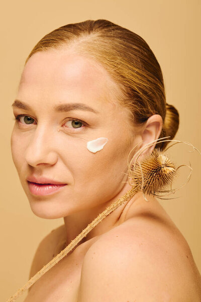 Эта красивая плюс размер женщина мягко наносит крем на щеку, источая уверенность и элегантность.