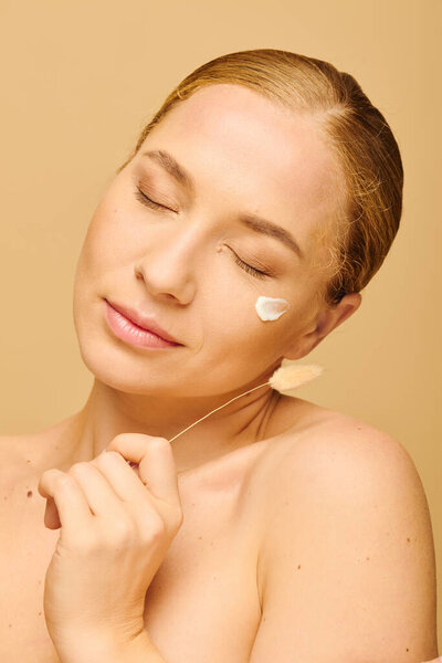 Молодая красивая женщина плюс размер расслабляет при нанесении крема на лицо, наслаждаясь уходом за собой.